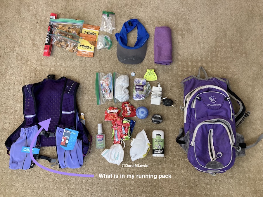 A purple running vest on the left; supplies described in blog post in the middle laid out on the ground, and my old purple backpack used for running on the right. 