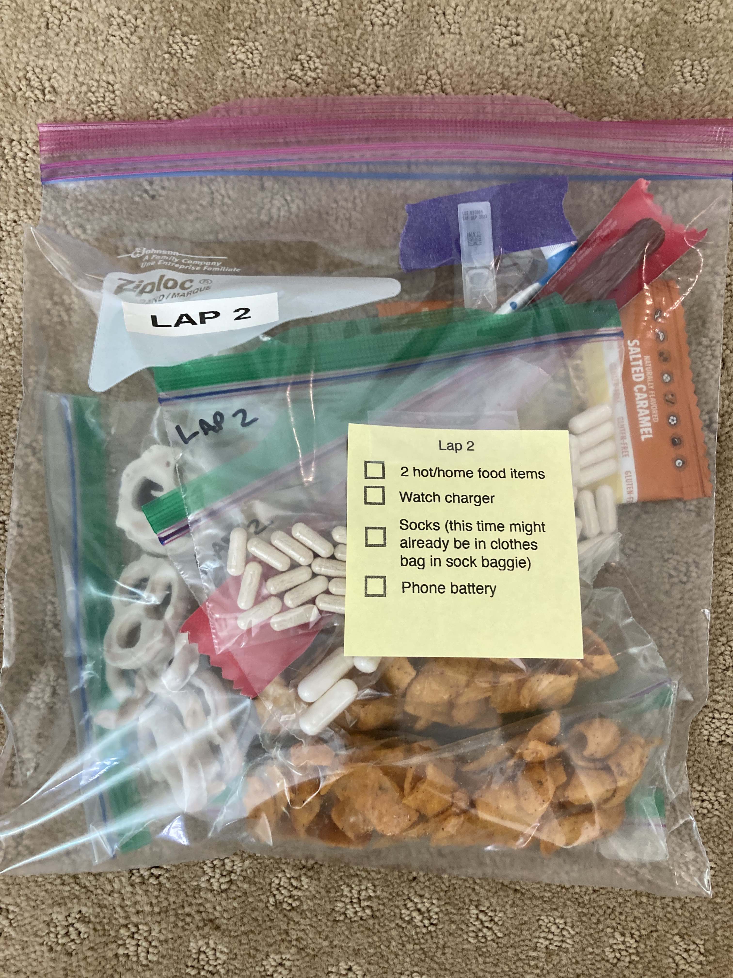 A gallon bag containing the enzymes, electrolytes, and snacks for each lap of my ultramarathon. Atop the bag is a printed sticky note with reminders of other fresh supplies my husband will bring each time.
